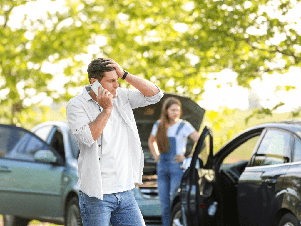 Two people outside of their crashed cars. They look stressed and are on the phone.
